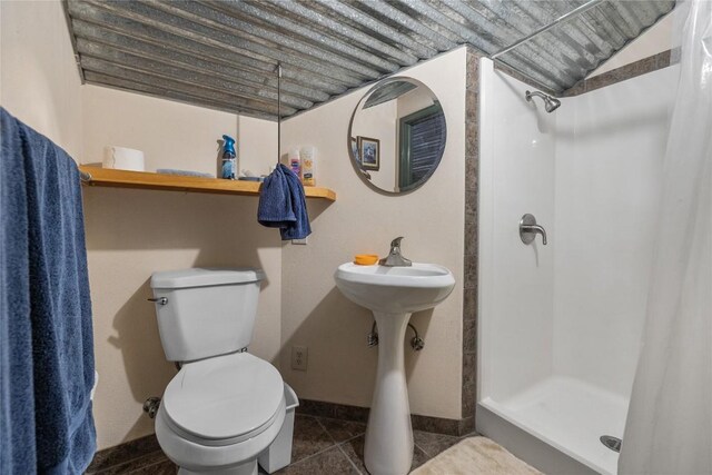 full bath featuring toilet, baseboards, a shower stall, and tile patterned flooring