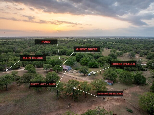 aerial view at dusk featuring a wooded view