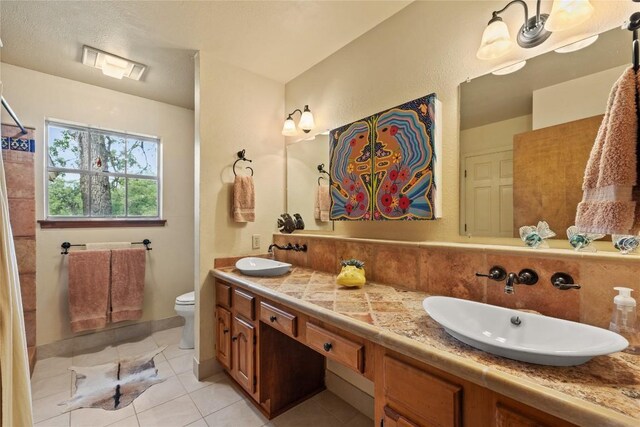 bathroom with tile patterned flooring, a sink, decorative backsplash, and toilet