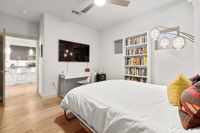bedroom with ceiling fan, wood finished floors, and visible vents
