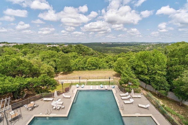 community pool featuring a forest view, fence, and a patio area