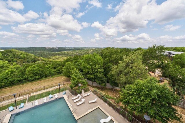 view of pool featuring fence and a forest view
