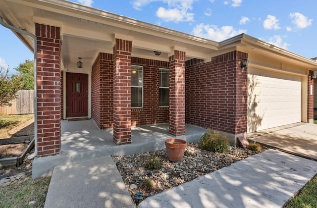 view of front of property featuring brick siding, fence, driveway, and a garage