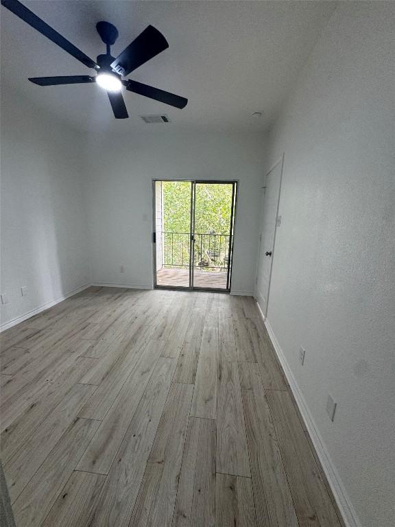 unfurnished room featuring baseboards, ceiling fan, wood finished floors, and visible vents