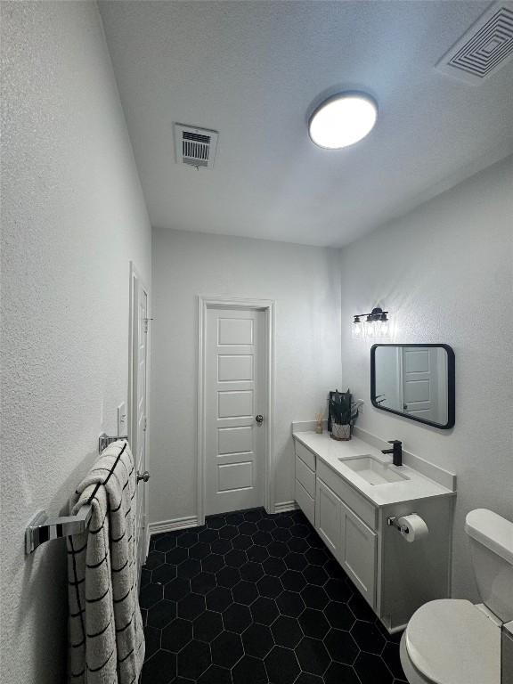 bathroom with vanity, toilet, and visible vents