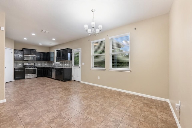 349 Eagle Brook Ln, Buda, TX 78610 - kitchen with appliances with stainless steel finishes, dark cabinetry, a chandelier, tasteful backsplash, and baseboards