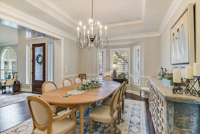 dining area featuring an inviting chandelier, ornamental molding, a tray ceiling, and dark wood finished floors