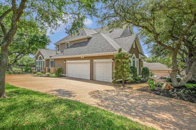 view of front facade featuring driveway, a garage, fence, a shingled roof, and stucco siding