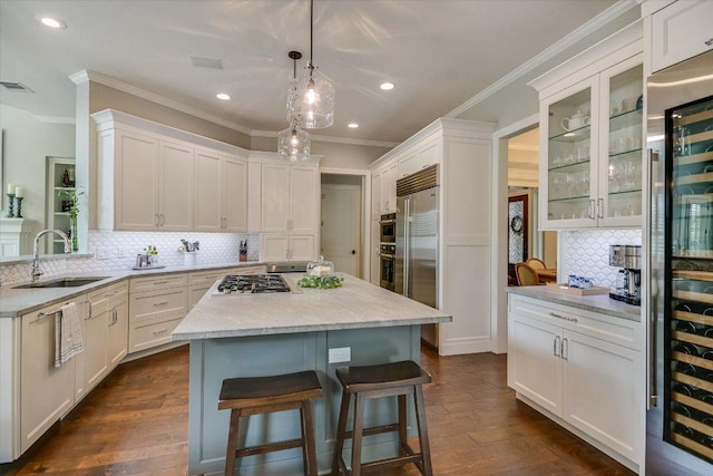 kitchen with backsplash, a kitchen bar, a sink, ornamental molding, and stainless steel appliances