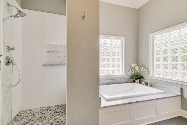 full bath with a healthy amount of sunlight, a walk in shower, and a bath