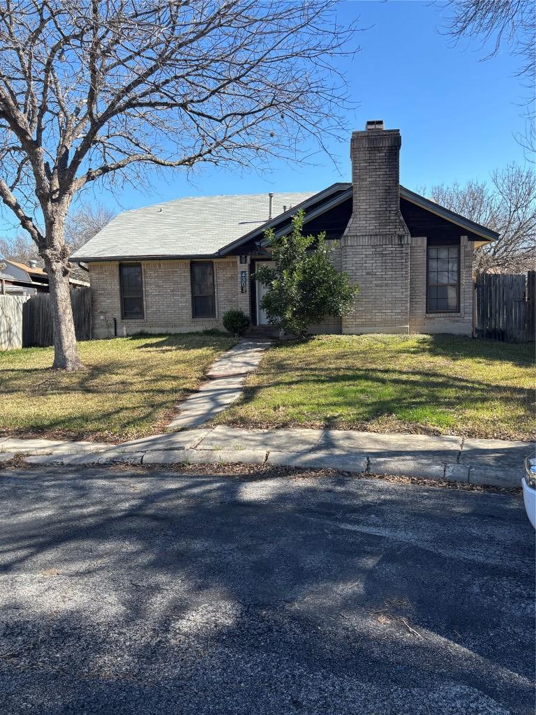ranch-style home with fence, a chimney, a front lawn, and brick siding