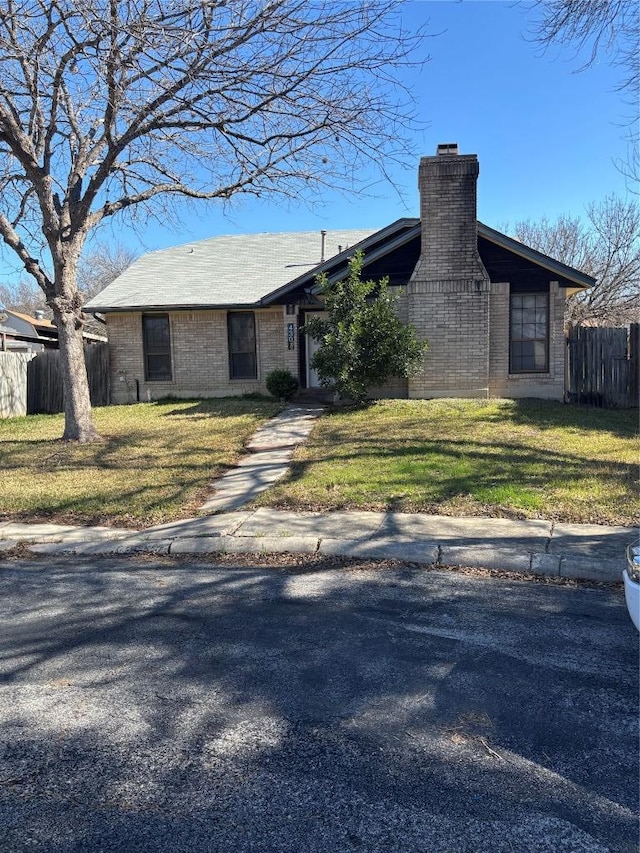 ranch-style home with fence, a chimney, a front lawn, and brick siding