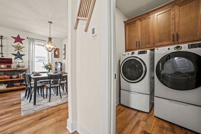 711 Livewater Ln, Georgetown, TX 78633 - washroom with separate washer and dryer, cabinet space, light wood finished floors, and a chandelier