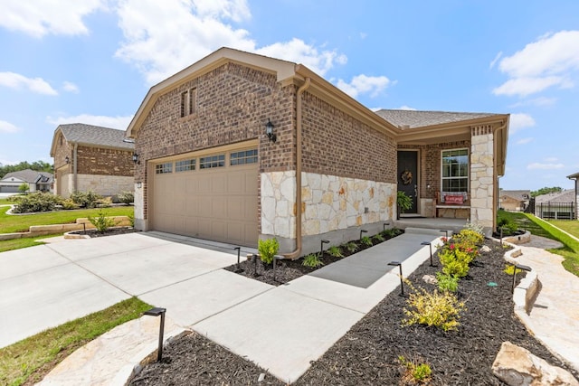 view of front facade featuring an attached garage, brick siding, stone siding, and concrete driveway