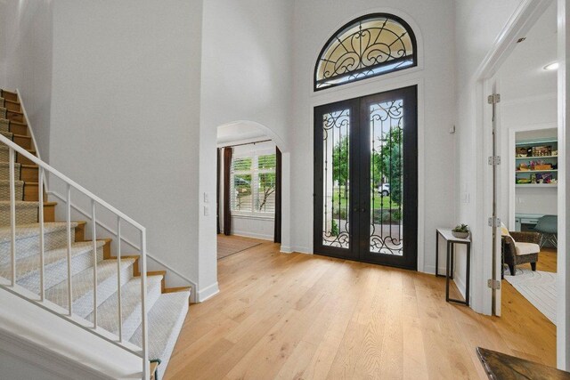 7921 W Rim Dr, Austin, TX 78731 - foyer entrance with french doors, arched walkways, stairs, wood finished floors, and a towering ceiling