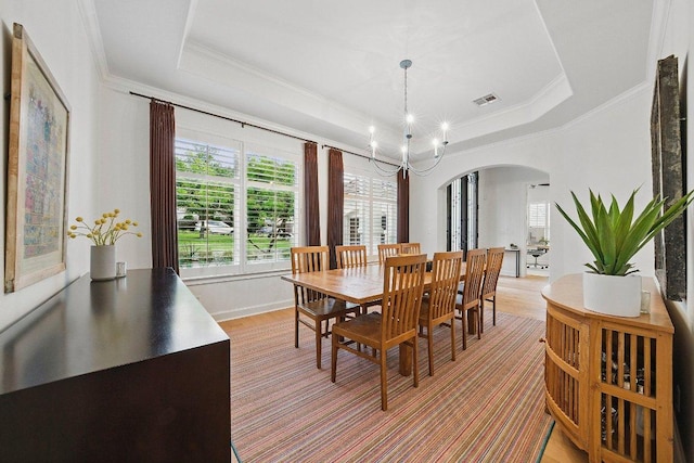 7921 W Rim Dr, Austin, TX 78731 - dining area with arched walkways, a chandelier, ornamental molding, light wood finished floors, and a tray ceiling