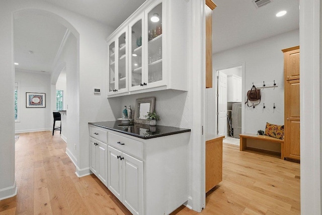 7921 W Rim Dr, Austin, TX 78731 - bar area featuring arched walkways, light wood-type flooring, washer / dryer, backsplash, and recessed lighting