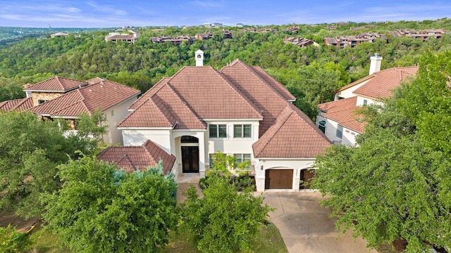 7921 W Rim Dr, Austin, TX 78731 - view of front of house with a tiled roof, stucco siding, a garage, and concrete driveway