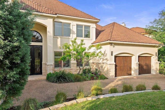 7921 W Rim Dr, Austin, TX 78731 - mediterranean / spanish-style house with a tiled roof, stone siding, an attached garage, and driveway