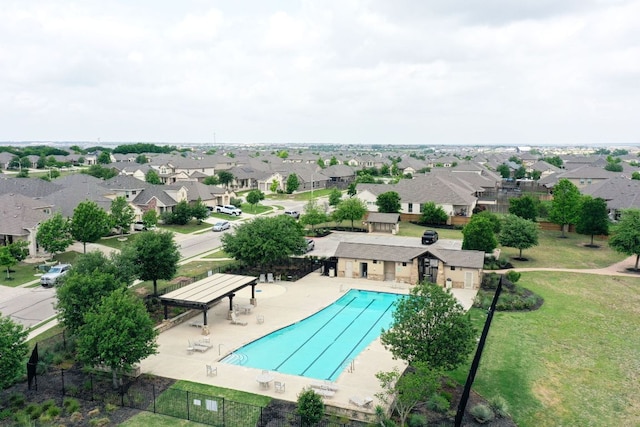 pool with a patio, fence, and a residential view