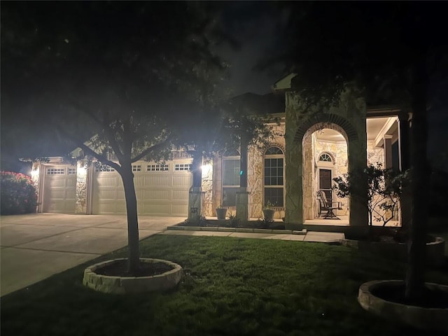 yard at night with driveway and a garage