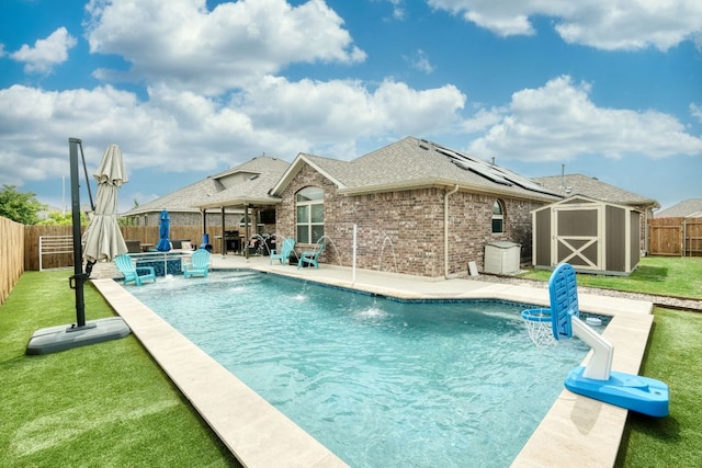 view of pool with a fenced backyard, a storage unit, a patio area, a lawn, and an outbuilding