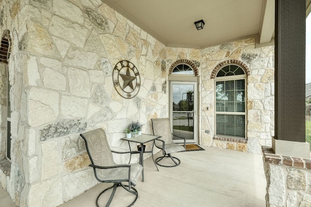 entrance to property with a porch and stone siding