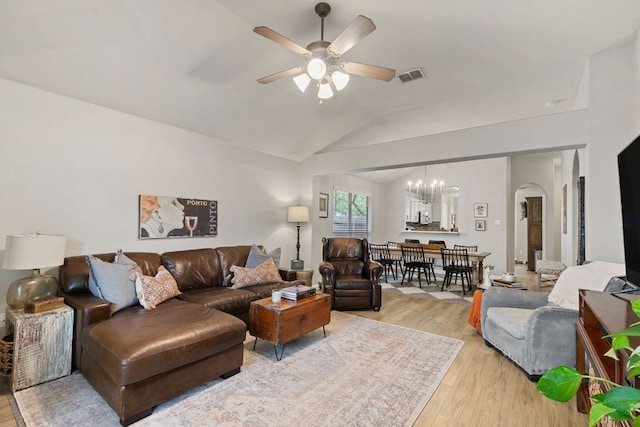 living room with visible vents, light wood-type flooring, arched walkways, ceiling fan with notable chandelier, and vaulted ceiling