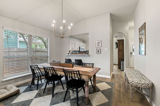 dining area featuring a notable chandelier, arched walkways, high vaulted ceiling, baseboards, and dark wood-style floors