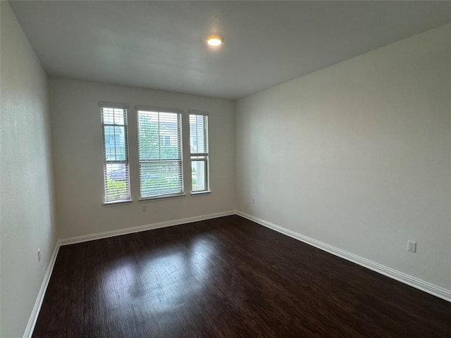 empty room with dark wood-style flooring and baseboards