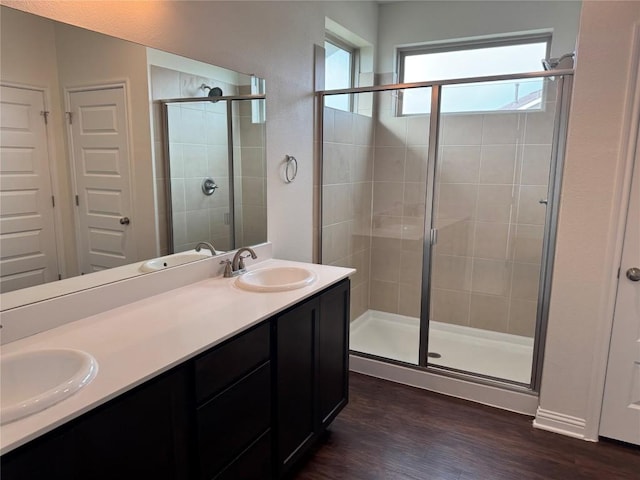 bathroom featuring wood finished floors, a sink, and a stall shower