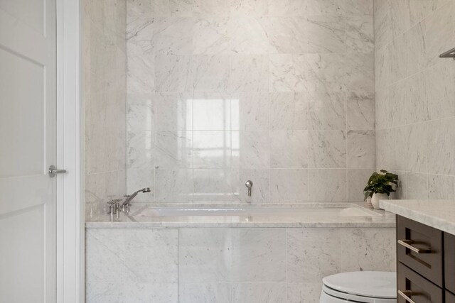 bathroom with vanity, a bath, and toilet