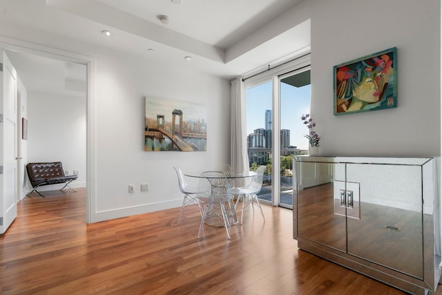dining room featuring recessed lighting, a city view, baseboards, and wood finished floors