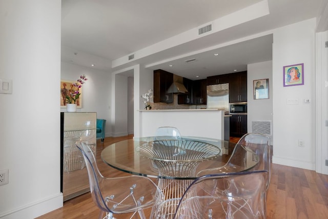dining space featuring light wood-style floors, baseboards, and visible vents