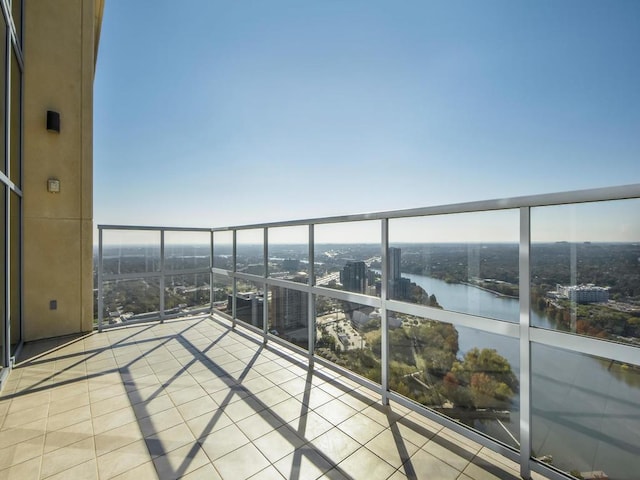 balcony featuring a water view, a sunroom, and a view of city
