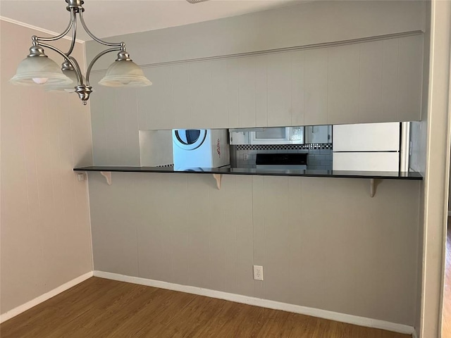 kitchen featuring white appliances, a kitchen breakfast bar, dark countertops, and wood finished floors