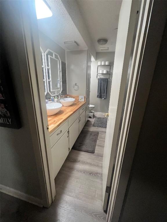 full bath with double vanity, baseboards, a sink, and wood finished floors