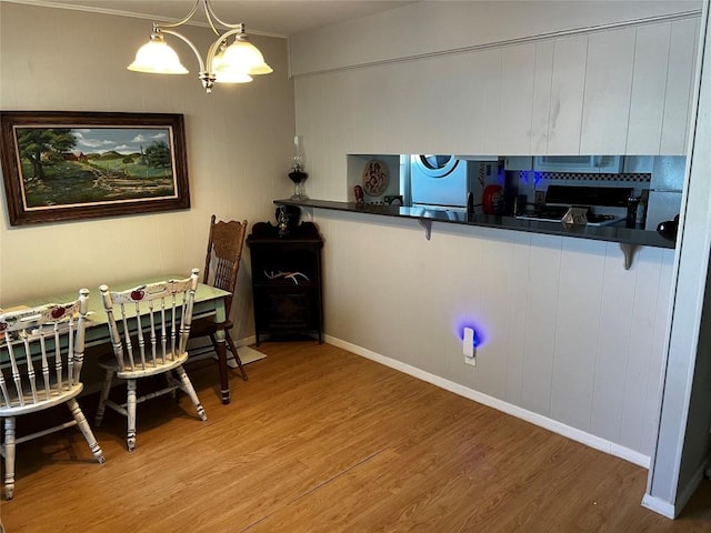 dining area featuring crown molding, baseboards, a chandelier, and wood finished floors