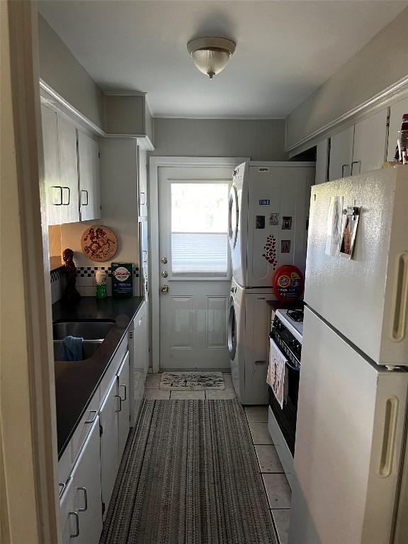 kitchen with stacked washer / dryer, dark countertops, refrigerator, freestanding refrigerator, and gas range oven
