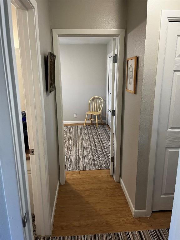 hallway with baseboards and wood finished floors