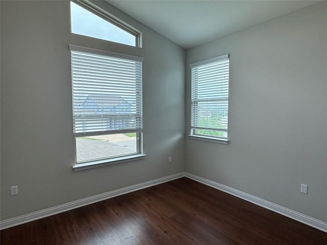 unfurnished room with baseboards and dark wood-style floors