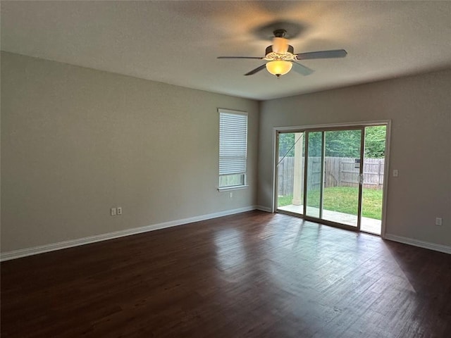 unfurnished room with baseboards, dark wood-type flooring, and ceiling fan