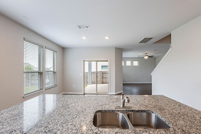 5816 Monmarte Cv, Austin, TX 78744 - kitchen featuring a sink, light stone counters, open floor plan, ceiling fan, and baseboards