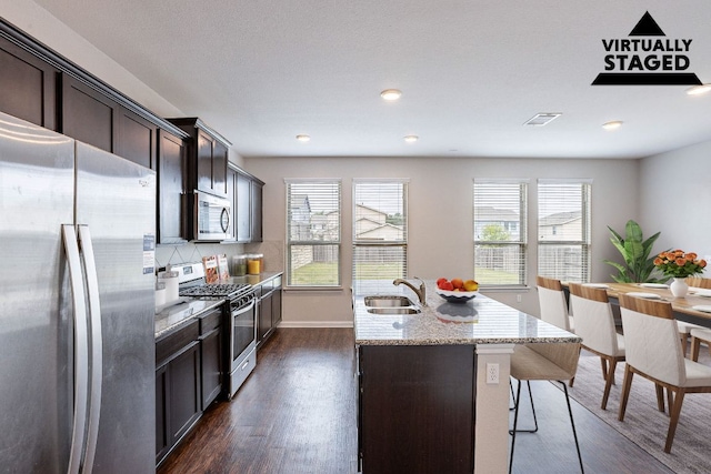 5816 Monmarte Cv, Austin, TX 78744 - kitchen with appliances with stainless steel finishes, a sink, dark wood finished floors, light stone countertops, and dark brown cabinets