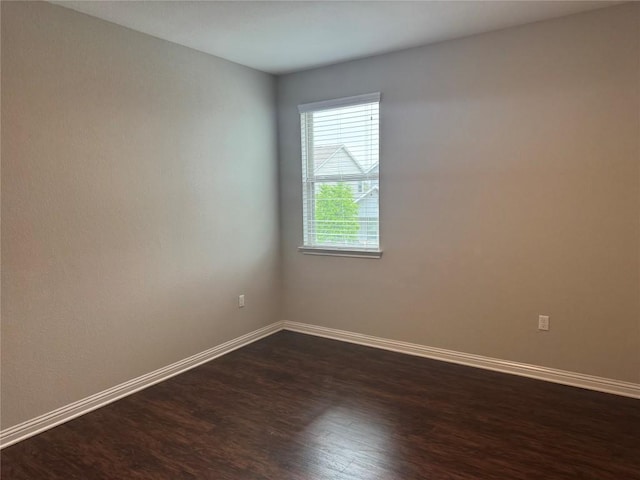 empty room featuring baseboards and dark wood-type flooring