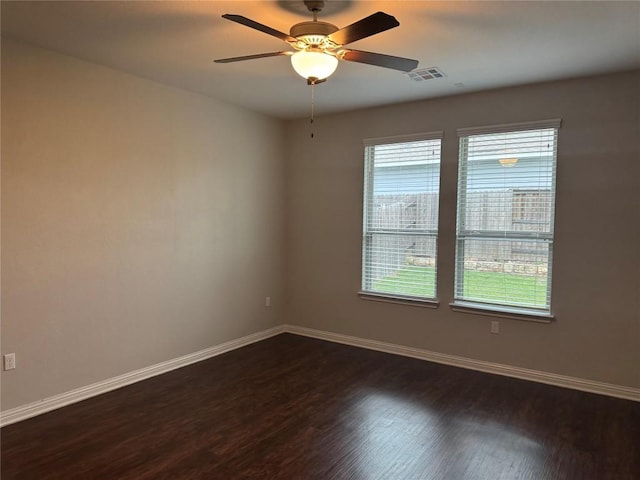 spare room featuring plenty of natural light, dark wood finished floors, baseboards, and visible vents
