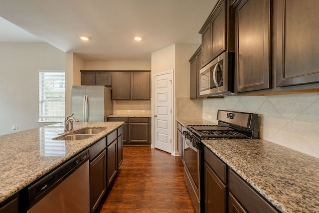 5817 Gerard Dr, Austin, TX 78744 - kitchen featuring stainless steel appliances, a sink, backsplash, light stone countertops, and dark wood finished floors