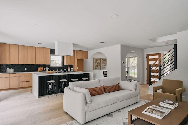 living room with arched walkways, recessed lighting, stairway, and light wood-type flooring