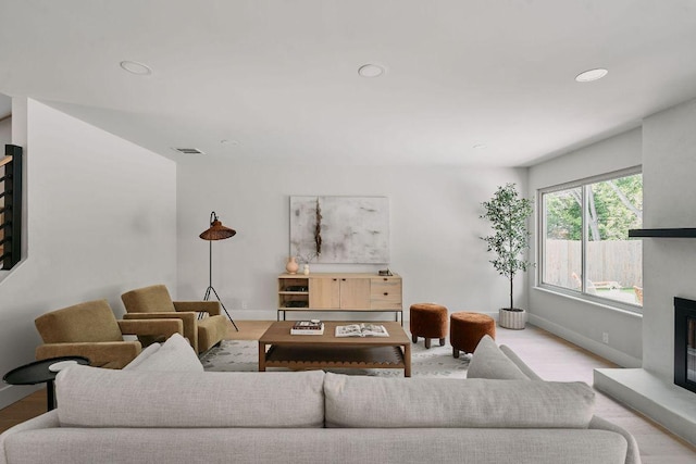 living area with visible vents, a fireplace with raised hearth, baseboards, and recessed lighting
