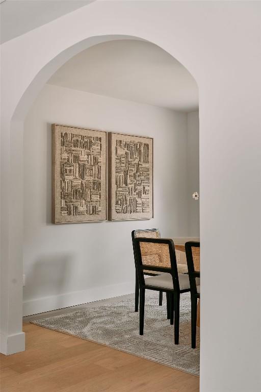 dining room featuring baseboards, arched walkways, and wood finished floors